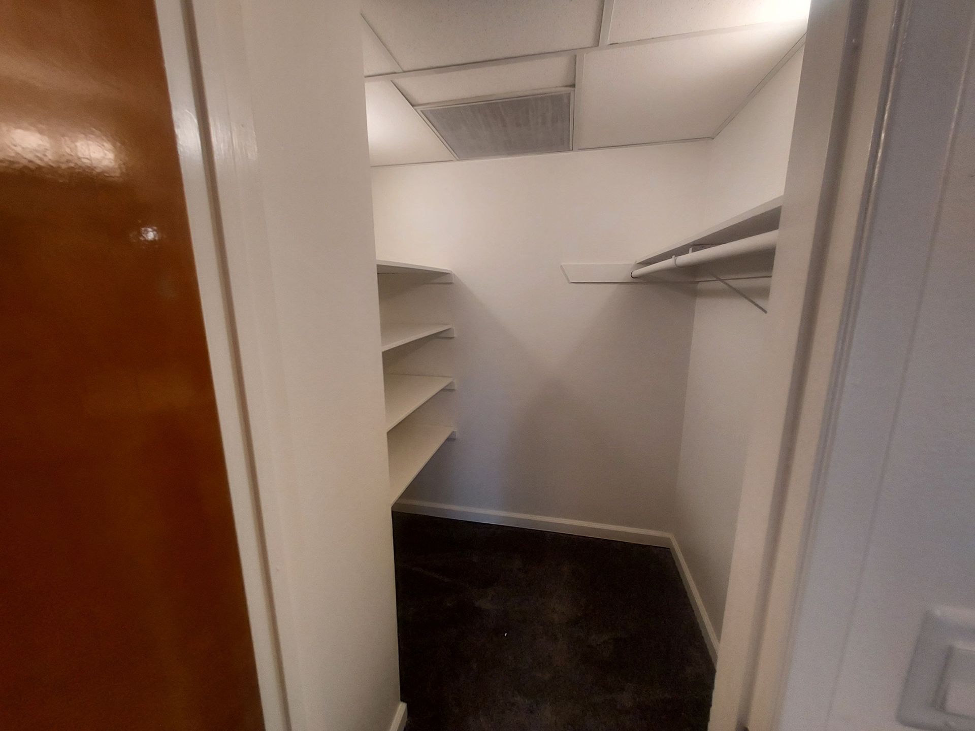 A small walk in closet with shelves and a door