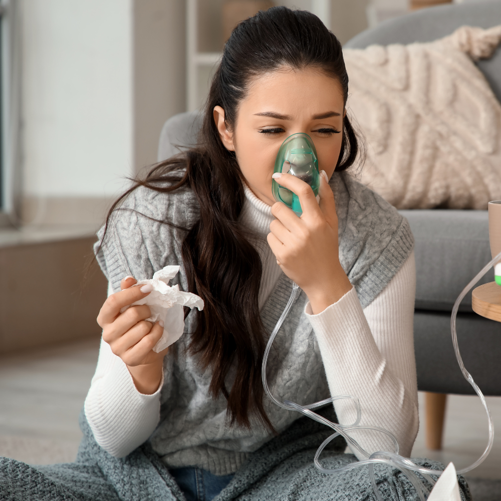 Woman using a nebulizer, holding tissue, indoors, possibly sick.
