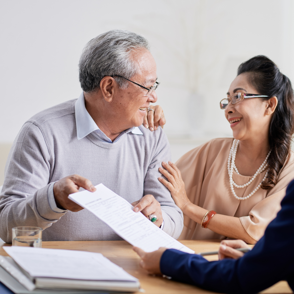 Older couple reviewing document with a person in a suit, sitting at a table.