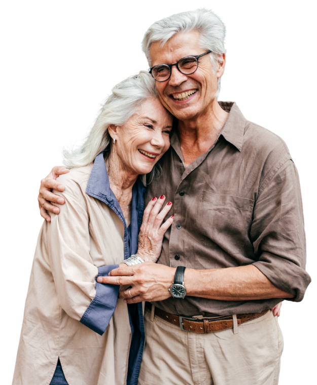 Older couple embracing and smiling. Man has glasses, woman has hand on his arm, both wear light colors.