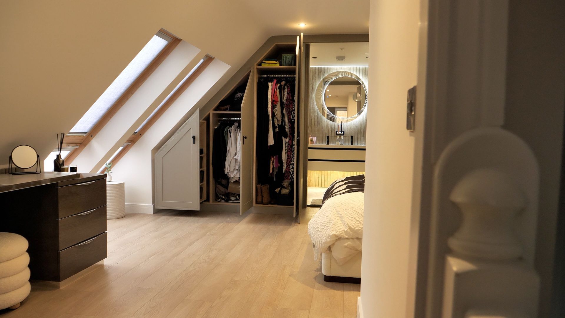 Bedroom with angled ceiling, built-in closet, vanity, and view of a bathroom through an open doorway.