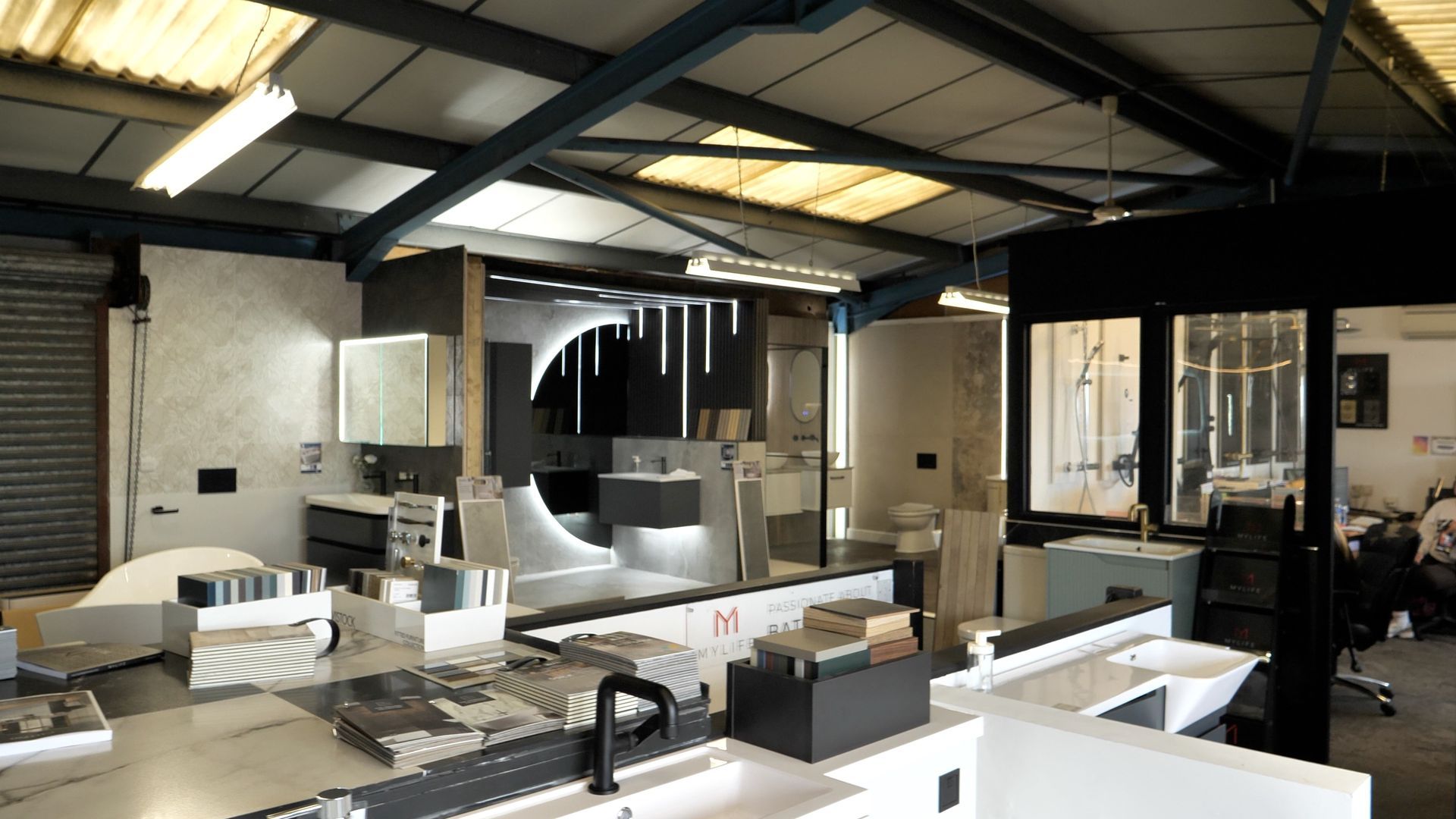 Beige kitchen with black stove, cabinets, and a farmhouse sink.