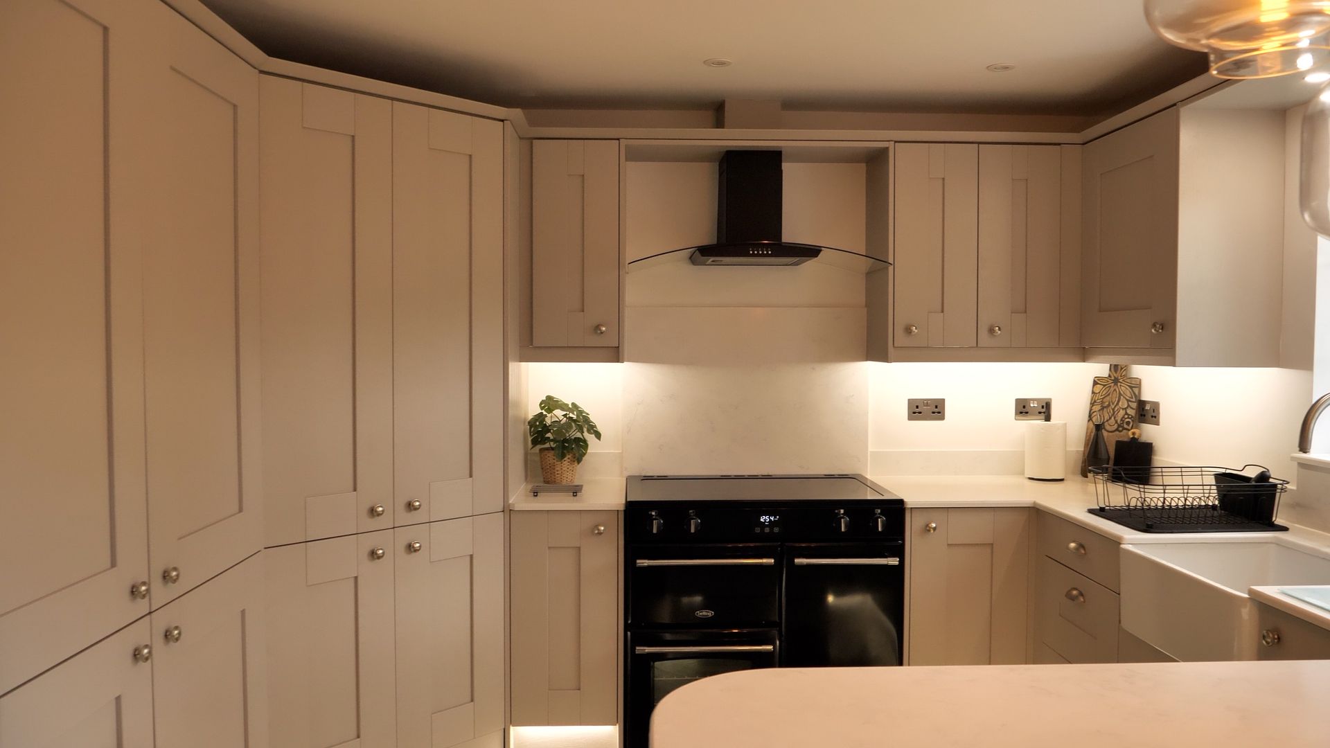Beige kitchen with black stove, cabinets, and a farmhouse sink.