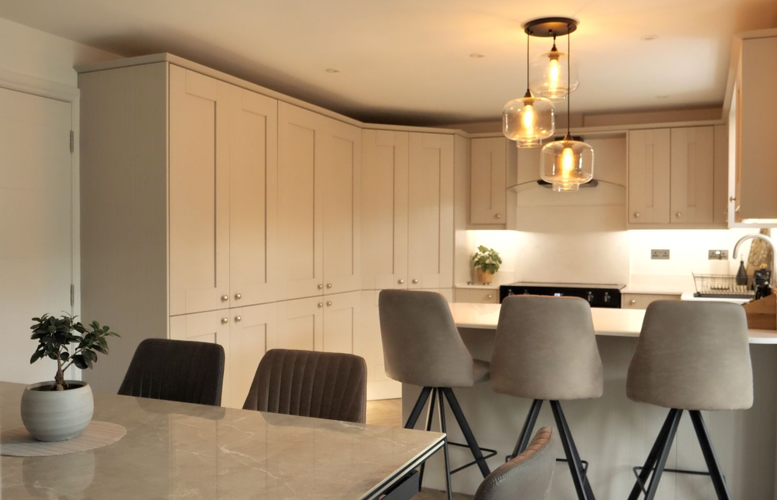 Modern kitchen with light cabinetry, island with bar stools, and pendant lights.