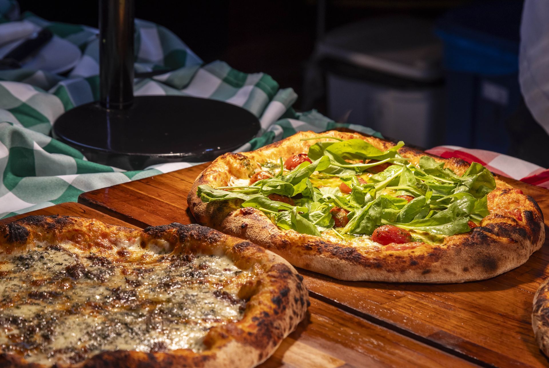 Duas pizzas estão sobre uma mesa de madeira.