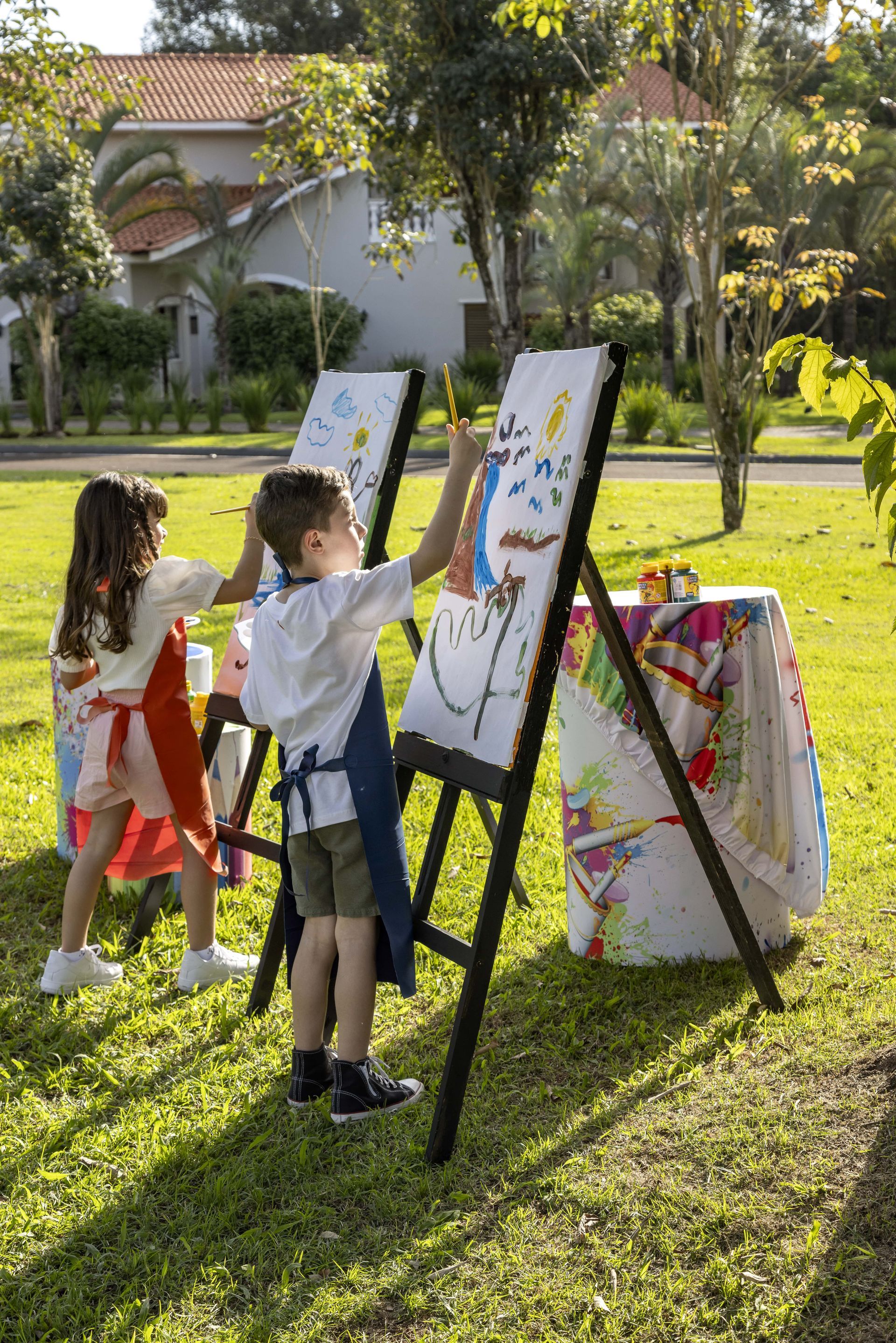 Um menino e uma menina estão pintando em um cavalete em um parque.