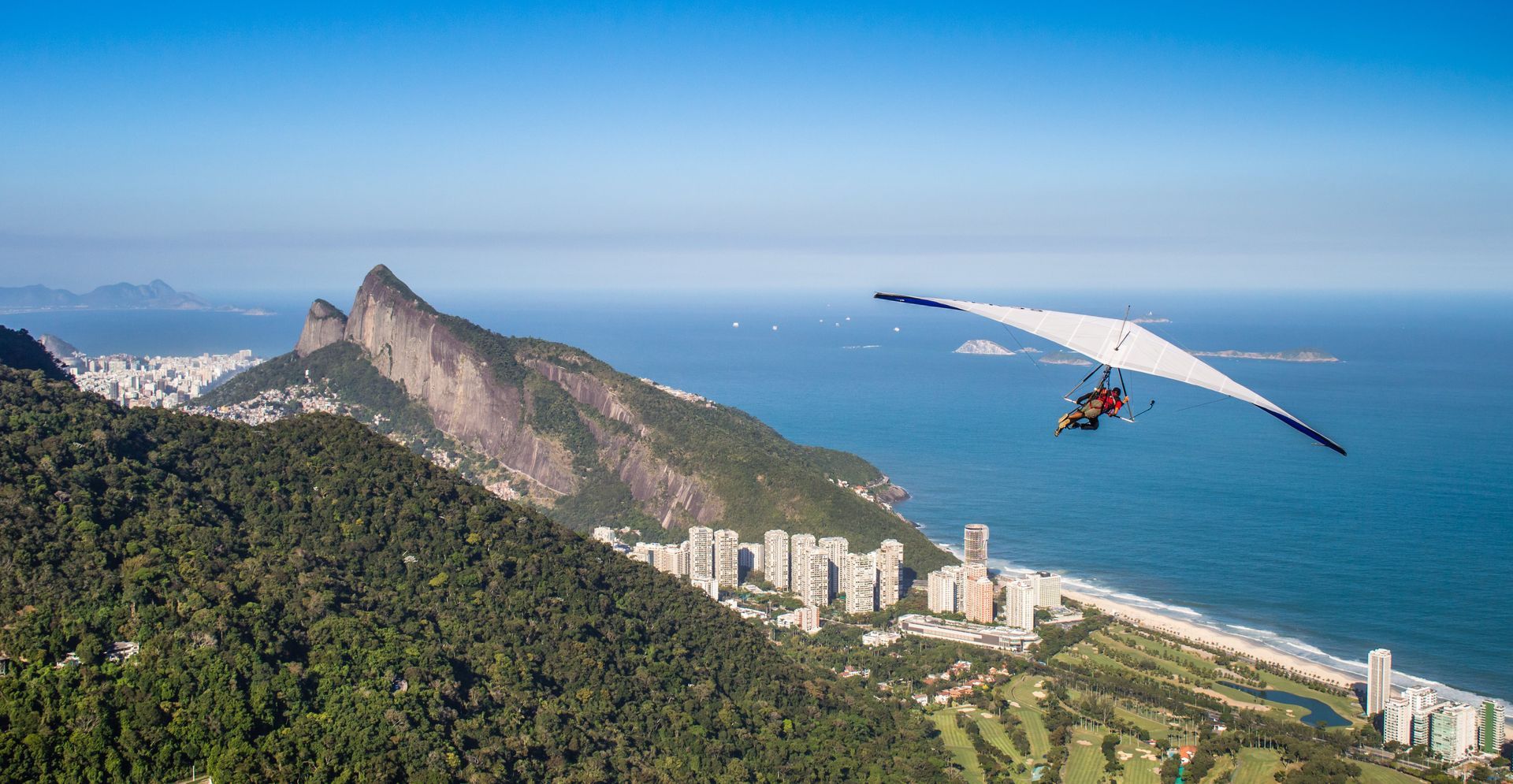 A person is flying a hang glider over a beach.