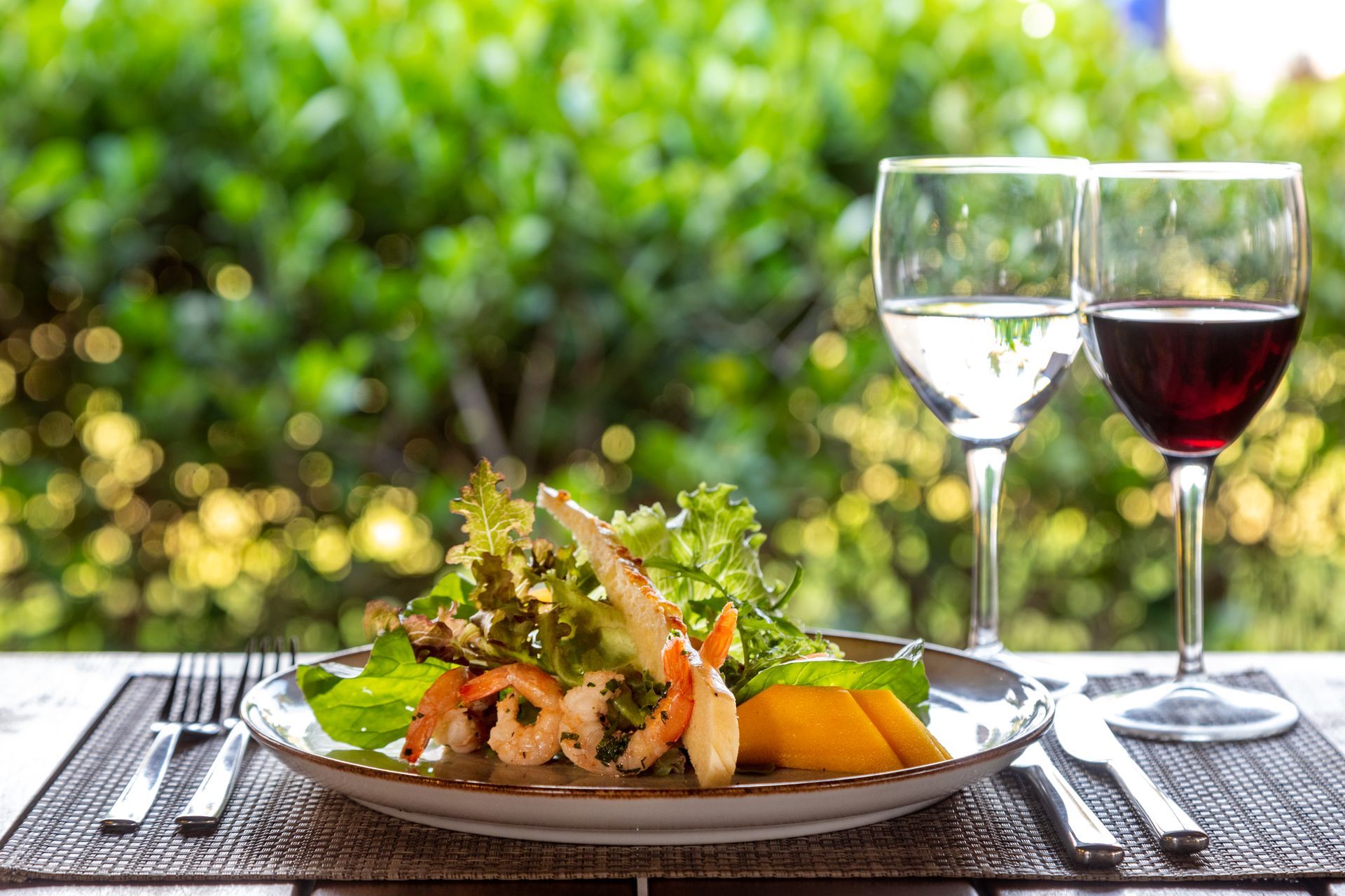 A plate of food and two glasses of wine on a table.