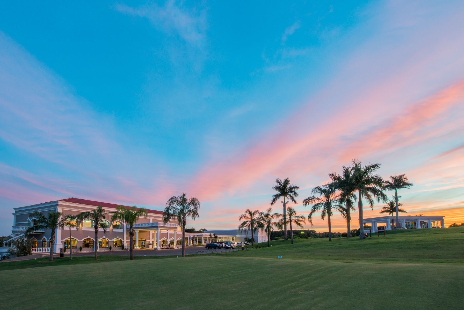 A large white building with palm trees in front of it.