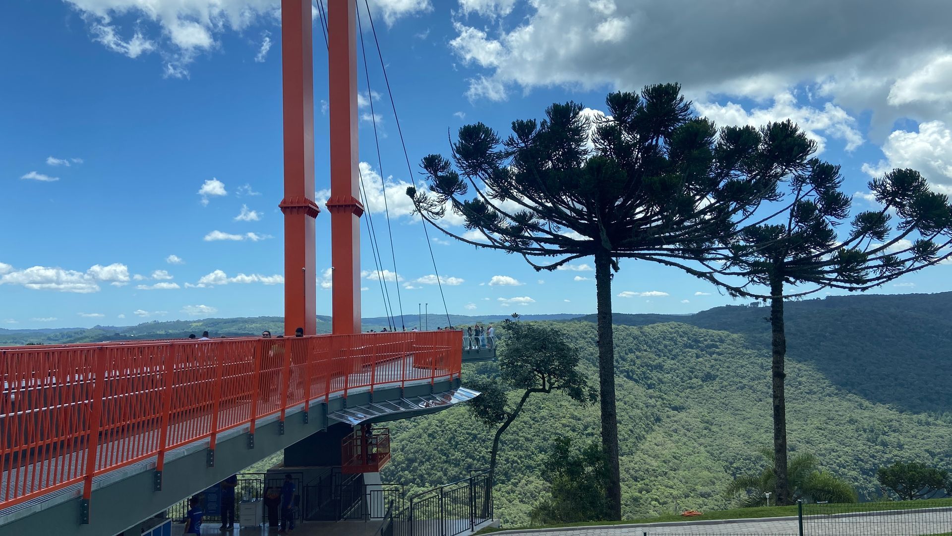 A bridge over a river with trees in the foreground and mountains in the background.