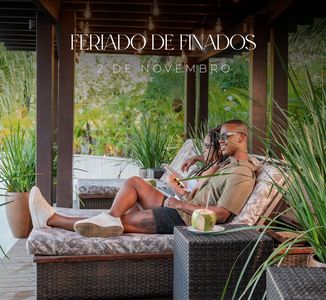 Casal relaxando em um pátio coberto com bebidas e plantas, sob uma placa de 