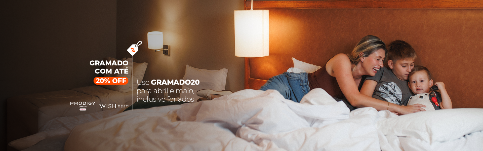Família aconchegada na cama sob cobertores brancos, ao lado de um abajur brilhante e com texto na tela.