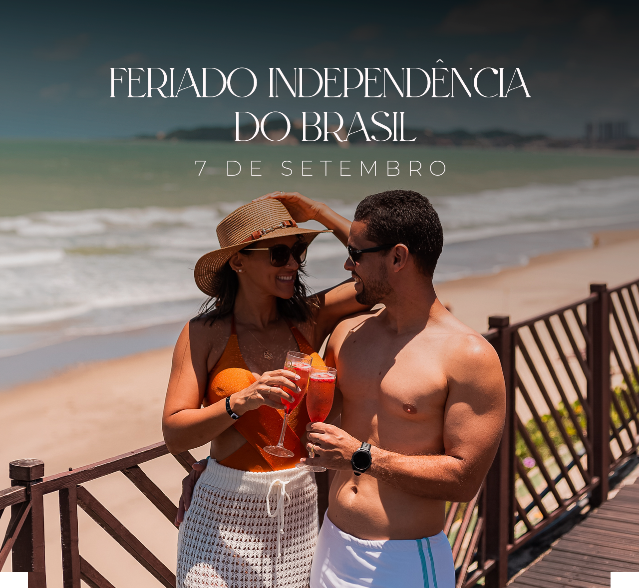 Couple at a beach boardwalk holding drinks, with text “Feriado Independência do Brasil” above them