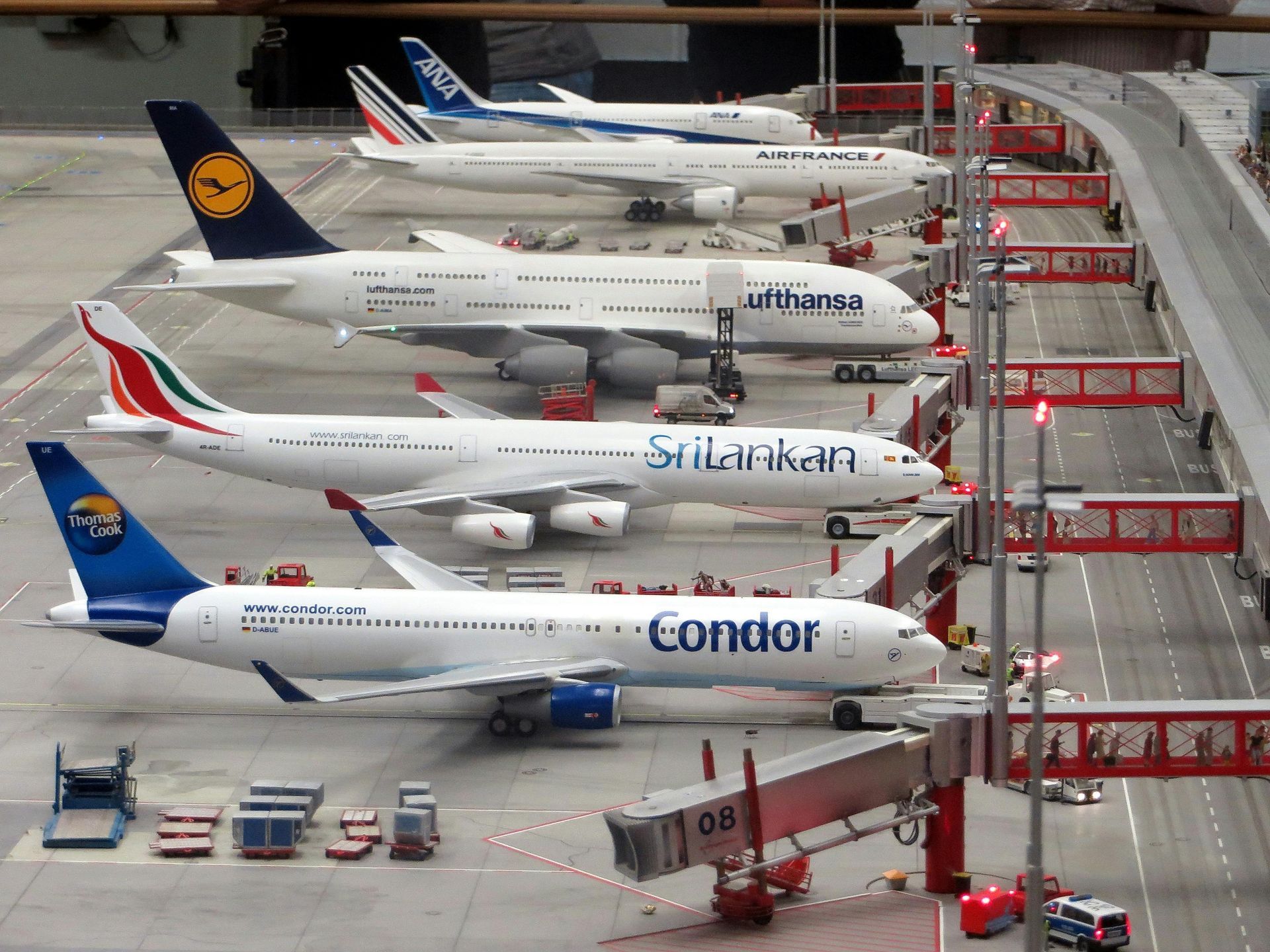 Miniature airport scene with model airplanes parked at gates; Lufthansa, SriLankan, and Condor planes are visible.
