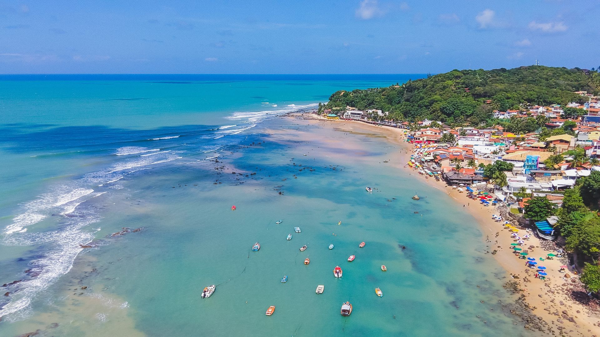 Uma vista aérea de uma praia com barcos na água.