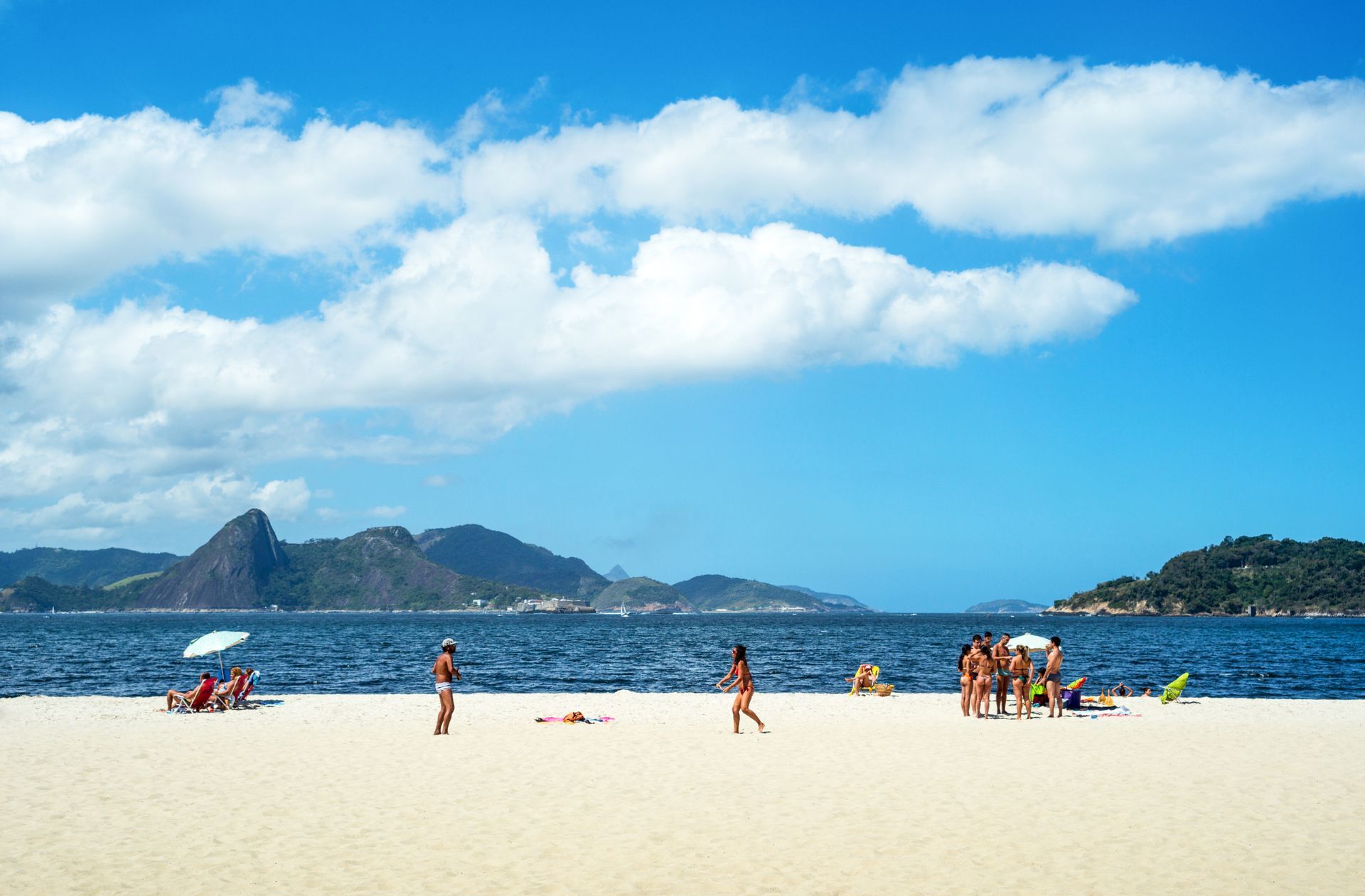 Um grupo de pessoas está caminhando em uma praia perto do oceano.