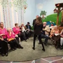 A woman is dancing in front of a group of people sitting in chairs.