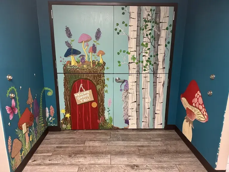 A room with a fairy door and mushrooms painted on the walls