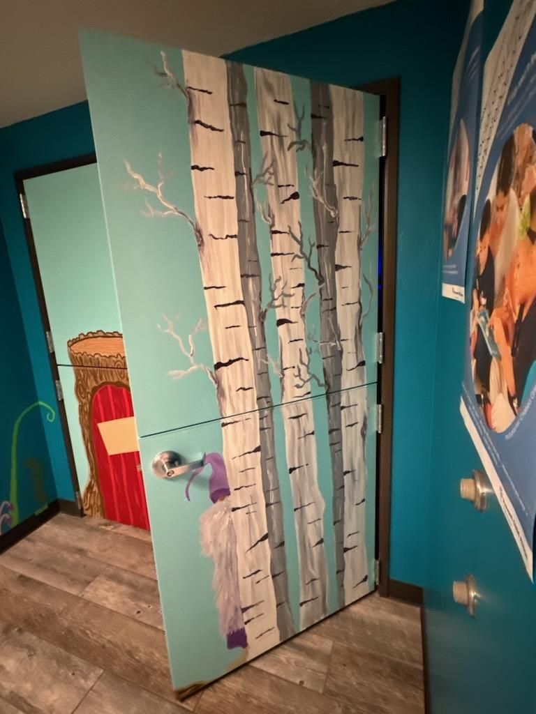 A door with trees painted on it in a room.