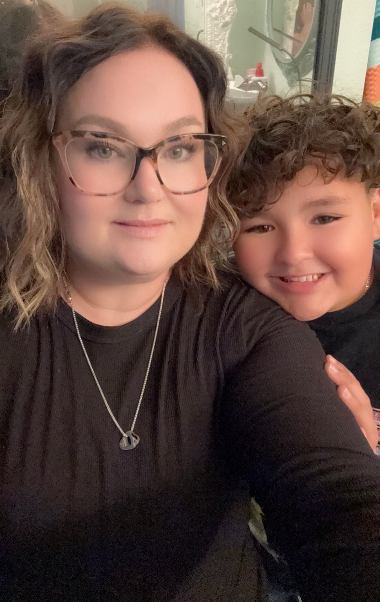 A woman wearing glasses is holding a young boy in her arms.