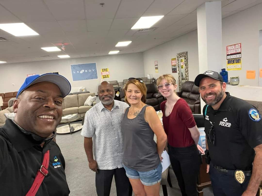 A group of people are posing for a picture in a furniture store.