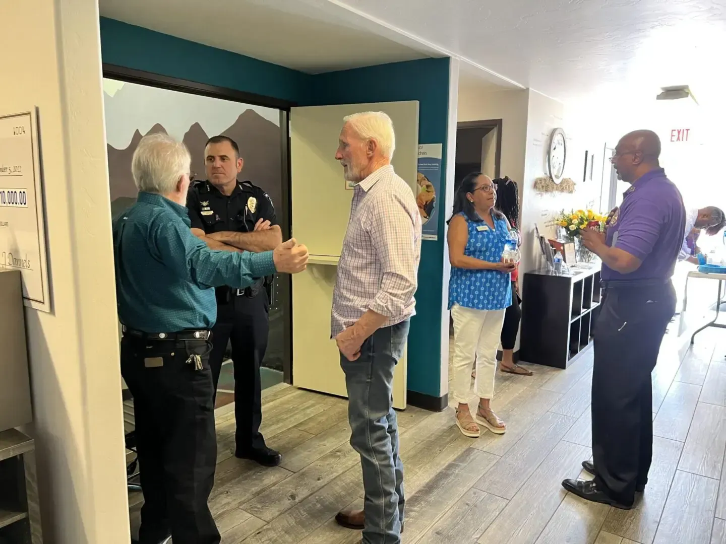 A group of people are standing in a room talking to each other.