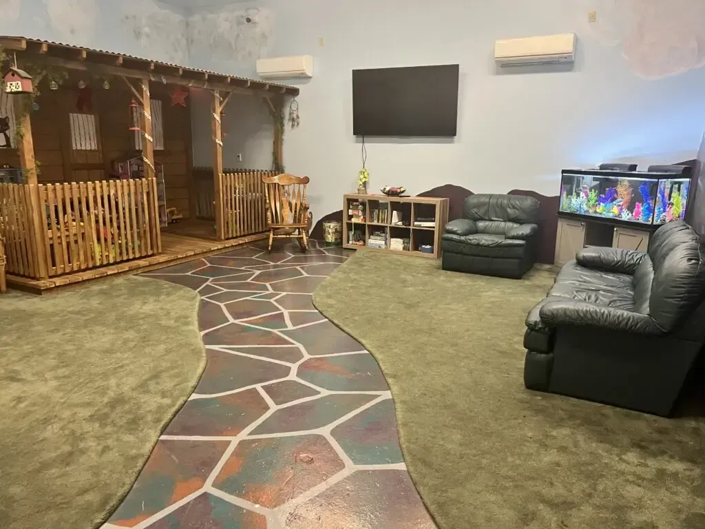 A living room with a couch , chairs and a television.