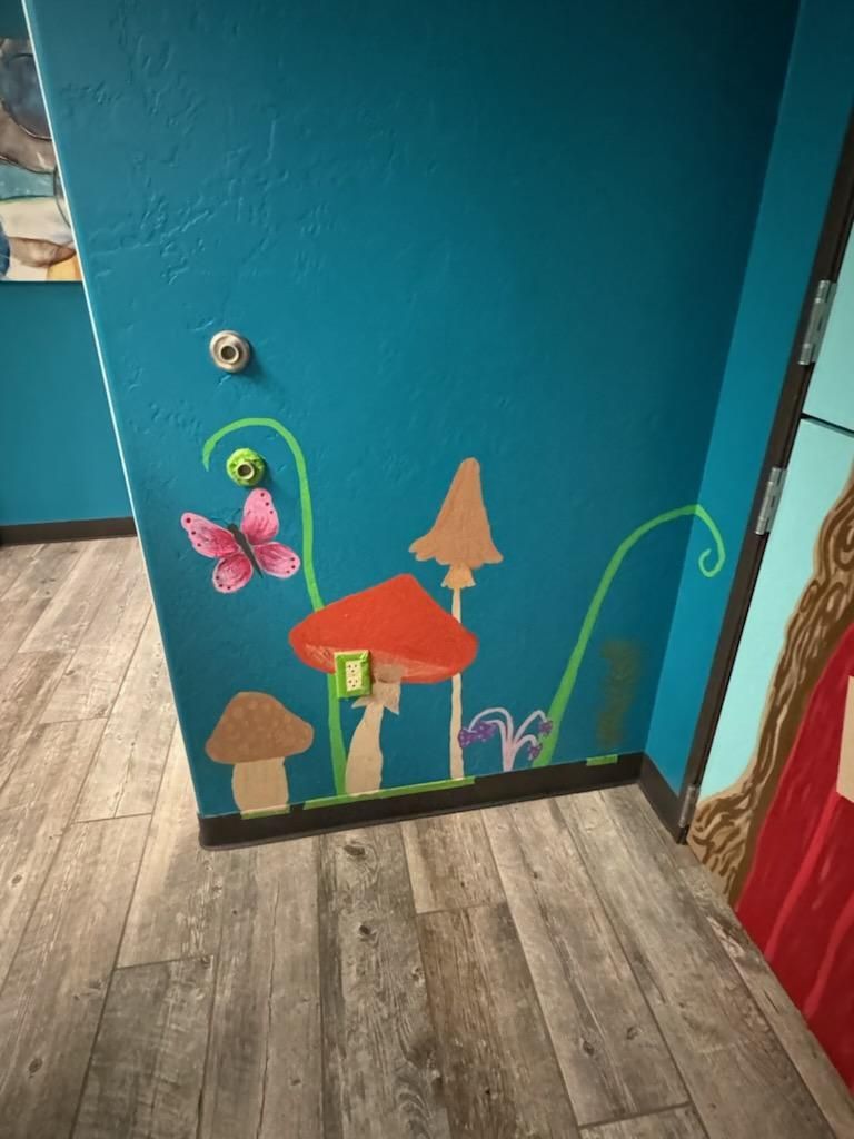 A blue wall with mushrooms and a butterfly painted on it