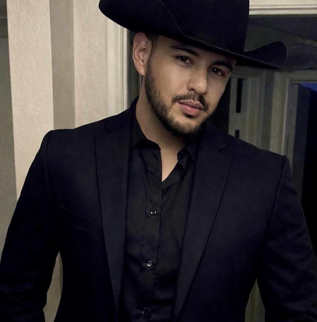 Man in black cowboy hat, suit, and button-down shirt, looking at the camera.