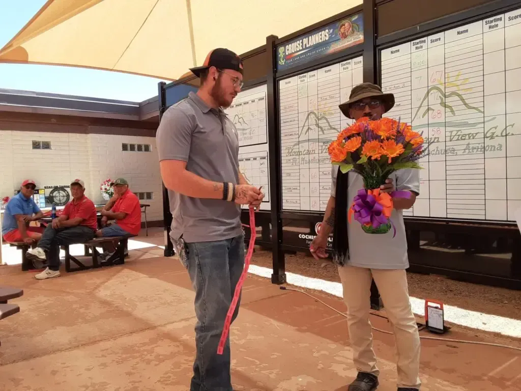 A man is holding a bouquet of flowers while standing next to another man.