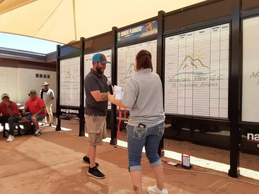 A man and a woman are standing in front of a white board.
