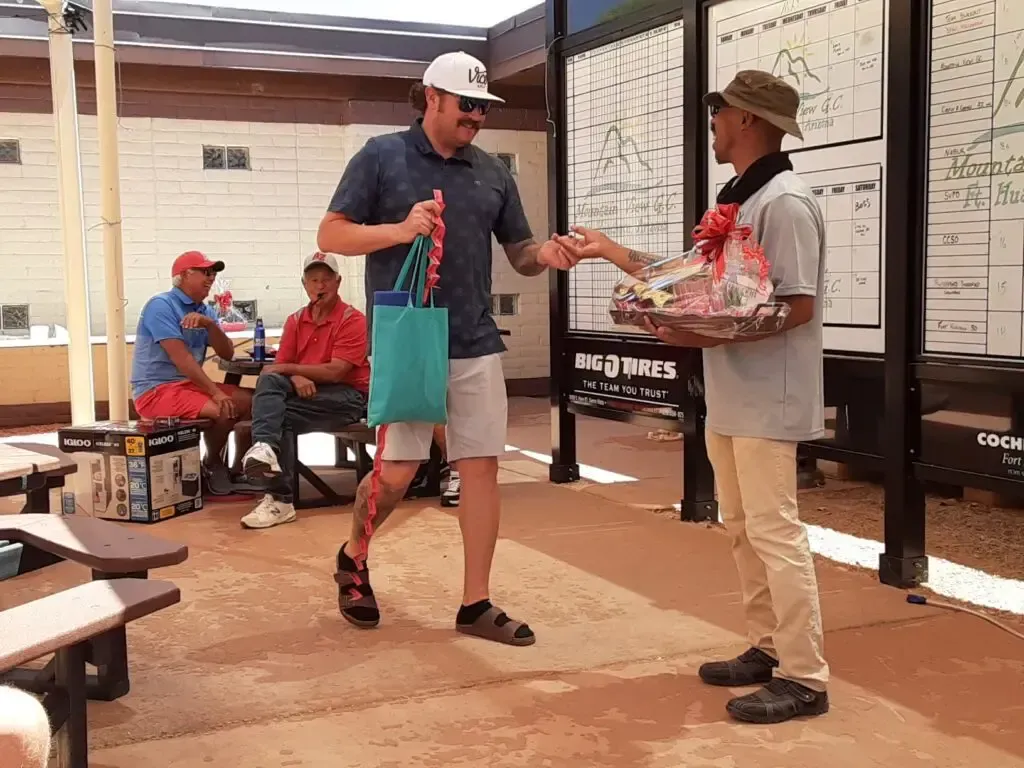 A man is giving a gift basket to another man.