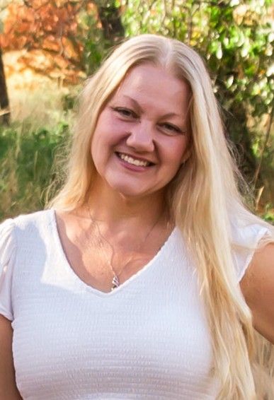 A woman with long blonde hair is smiling for the camera.