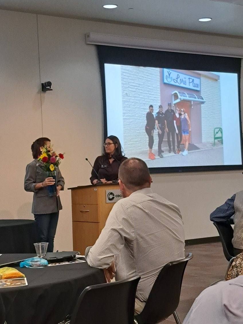 A woman is giving a presentation to a group of people in front of a large screen.