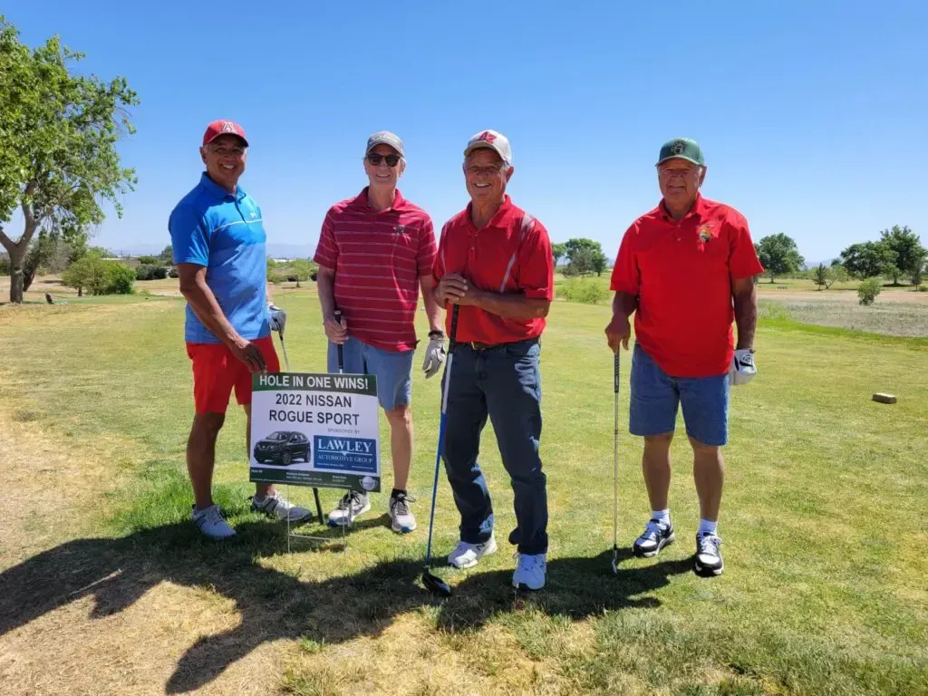 A group of men are standing on a golf course holding golf clubs.