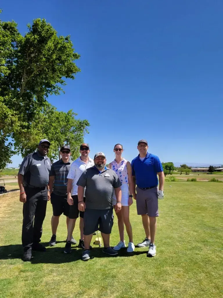 A group of people are posing for a picture on a golf course.
