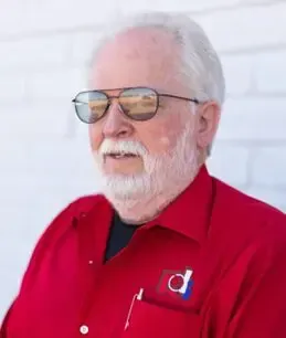 A man with a beard wearing sunglasses and a red shirt.