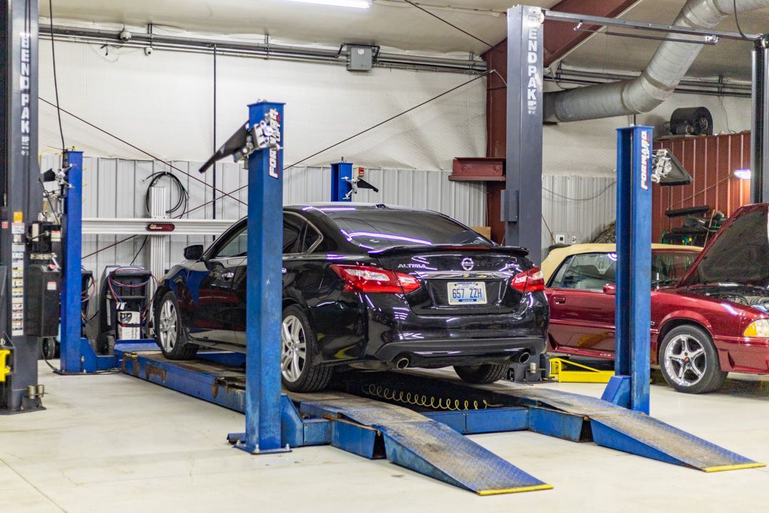 Black Sedan Positioned on Hydraulic Lift for Inspection | Tex's Transmissions Complete Auto & Truck Care