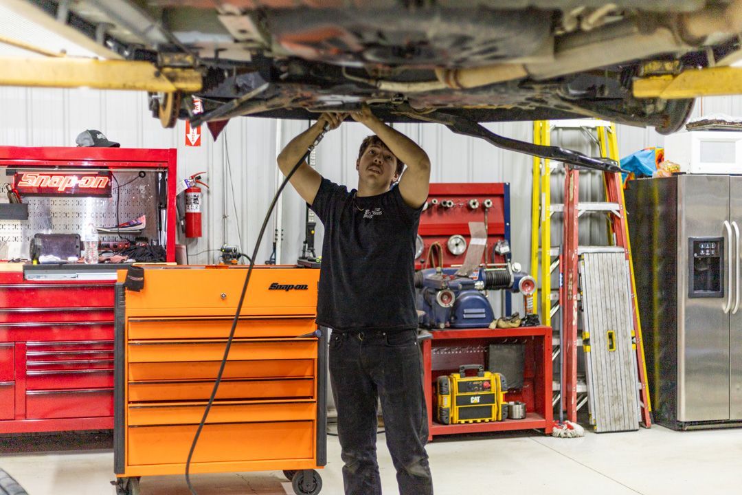 Technician Inspecting Undercarriage of Raised Vehicle | Tex's Transmissions Complete Auto & Truck Care