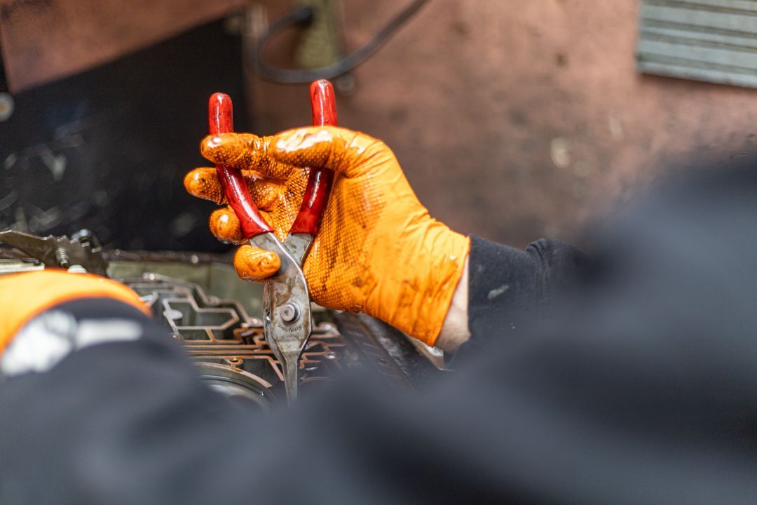 Mechanic Wearing Gloves Using Pliers on Engine Component | Tex's Transmissions Complete Auto & Truck Care