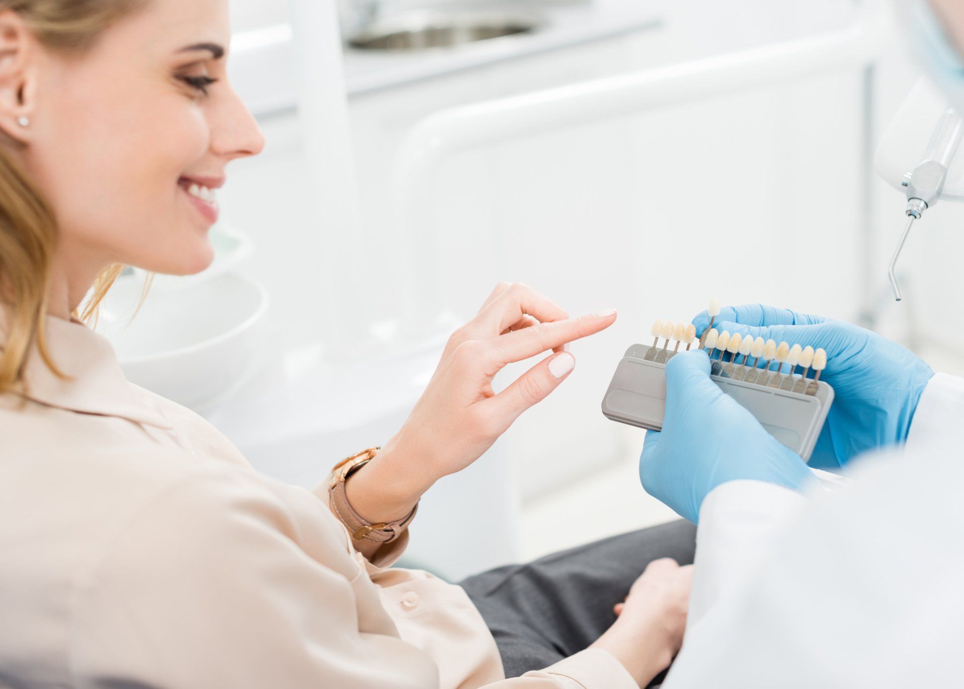 A woman is sitting in a dental chair while a dentist holds a model of her teeth