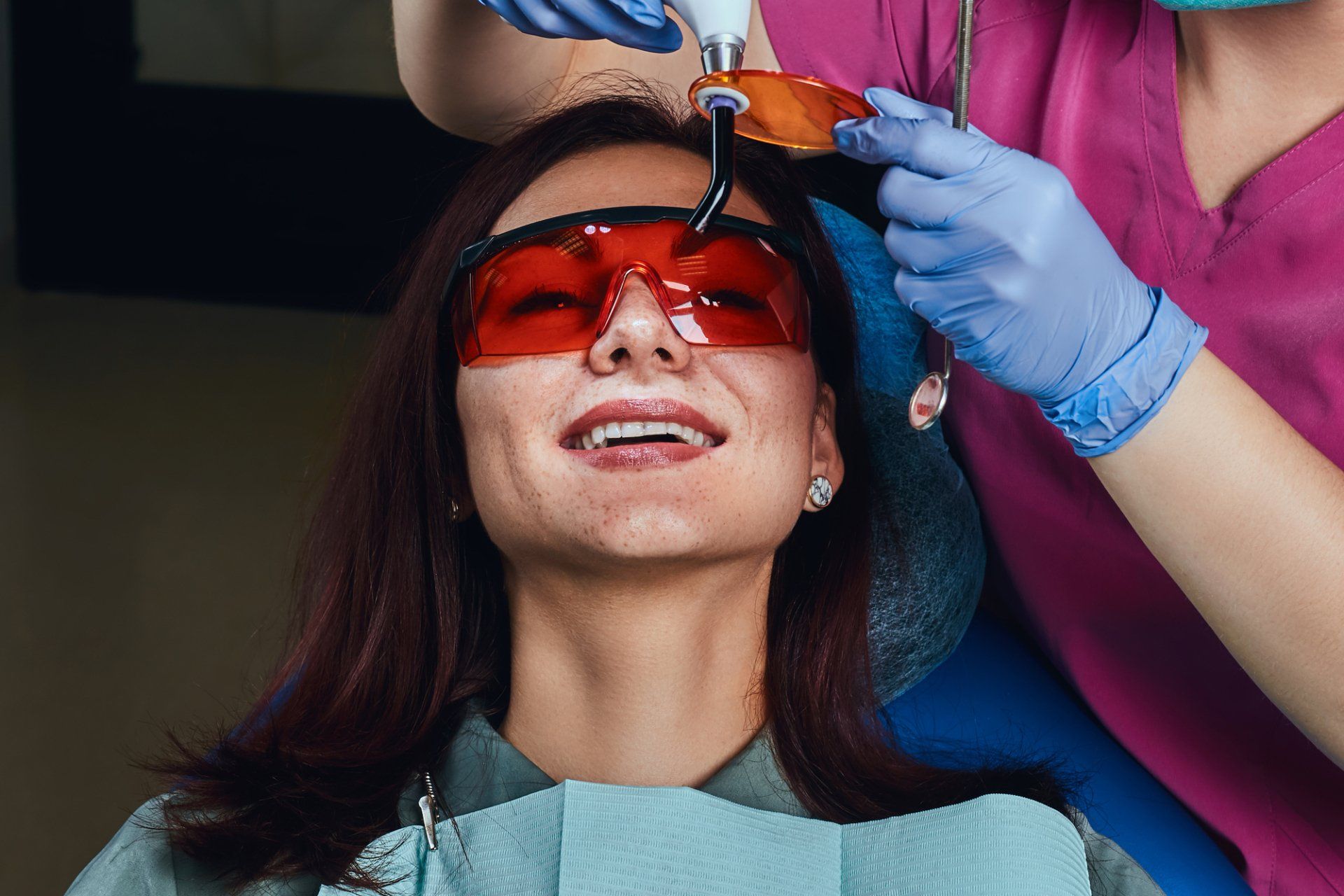 A woman is getting her teeth whitened by a dentist.