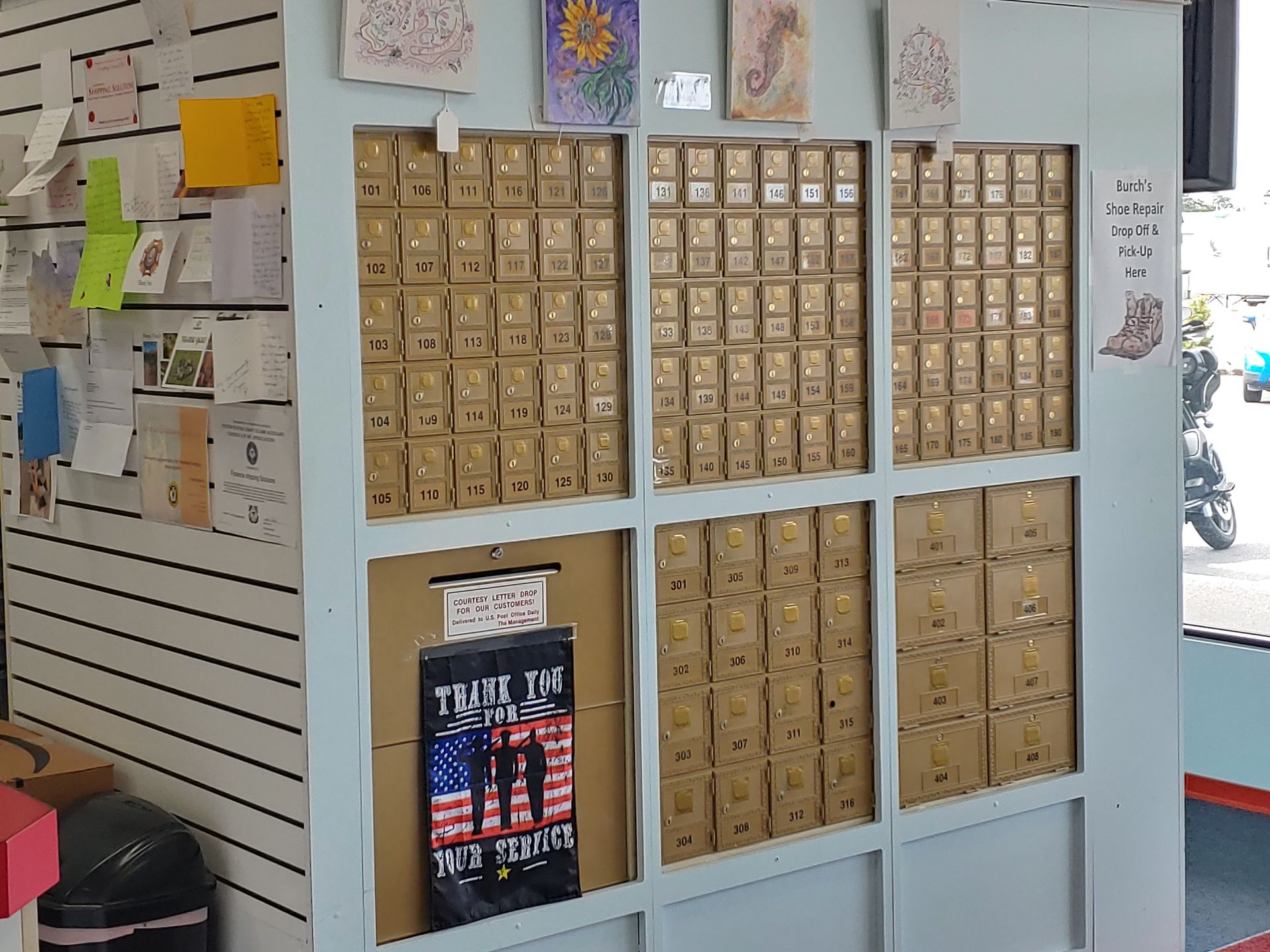 Three white mailboxes are sitting next to a red sign that says for rent