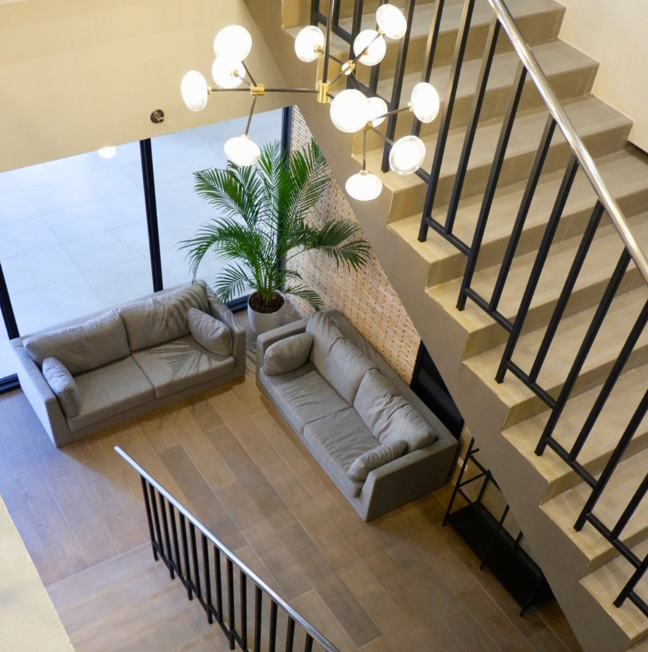 Modern interior with two gray sofas, staircase, and a chandelier.