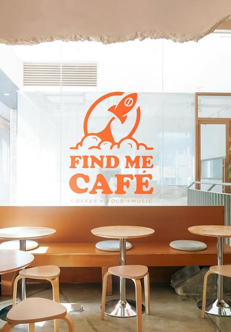 A cafe with tables and stools and a sign that says find me cafe