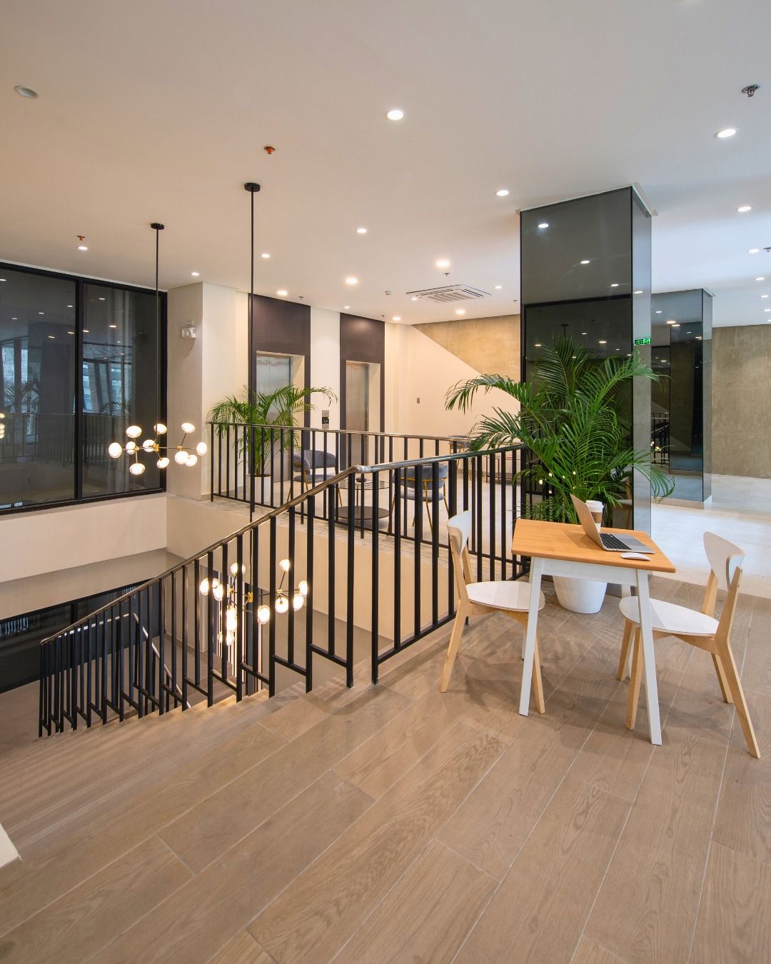 Modern interior with stairs, table, chairs, and plants; light wood and neutral colors.