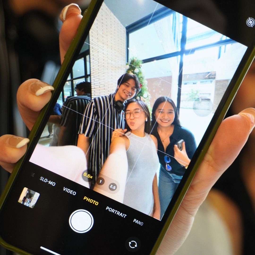 Four colleagues at a table, discussing work. One on phone, others looking at laptop and talking in an office.