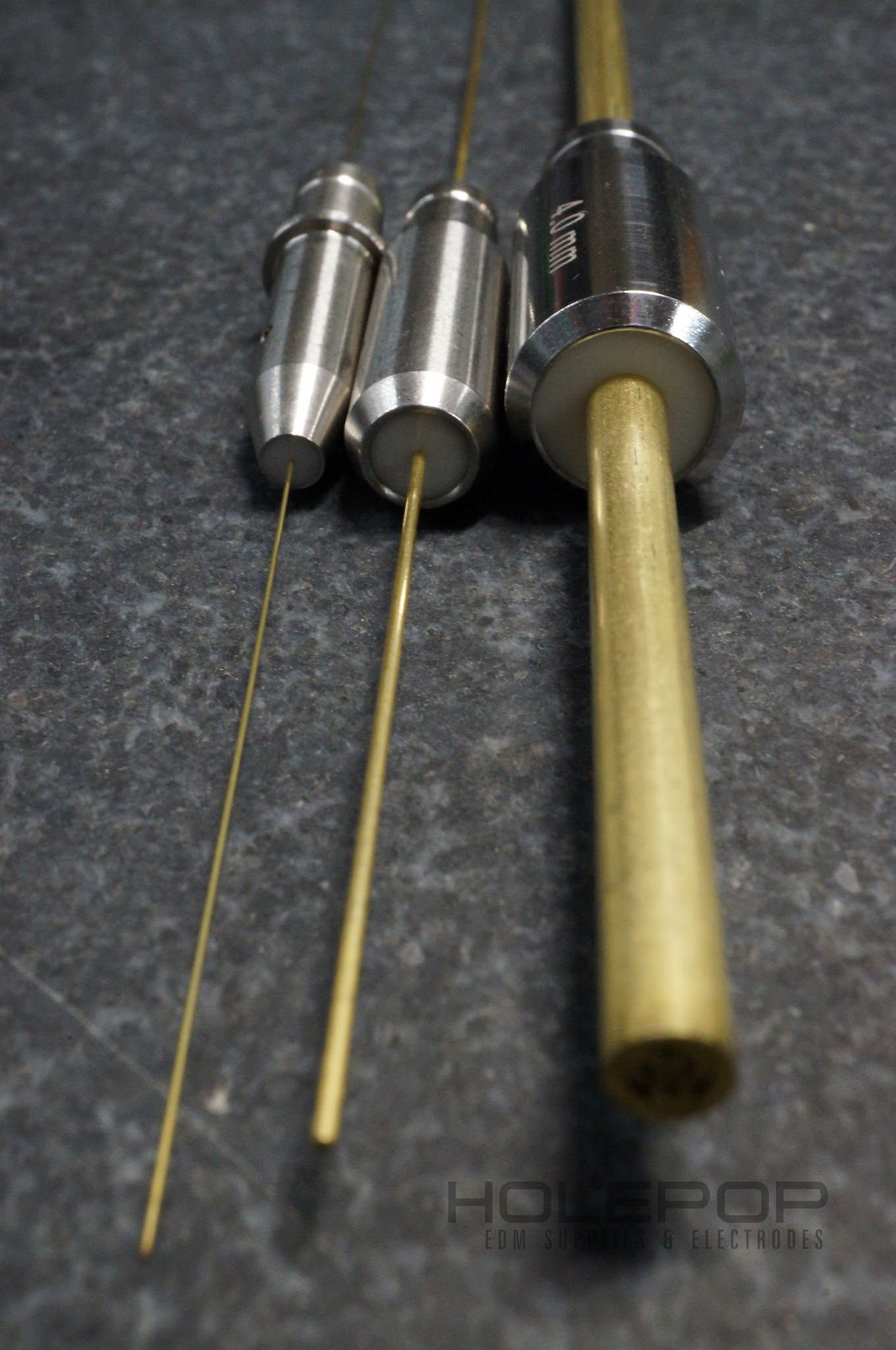 Three dental file tools with silver handles and thin gold tips on a dark surface