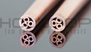 Four copper electrical cable ends with visible cross-sections on a gray surface