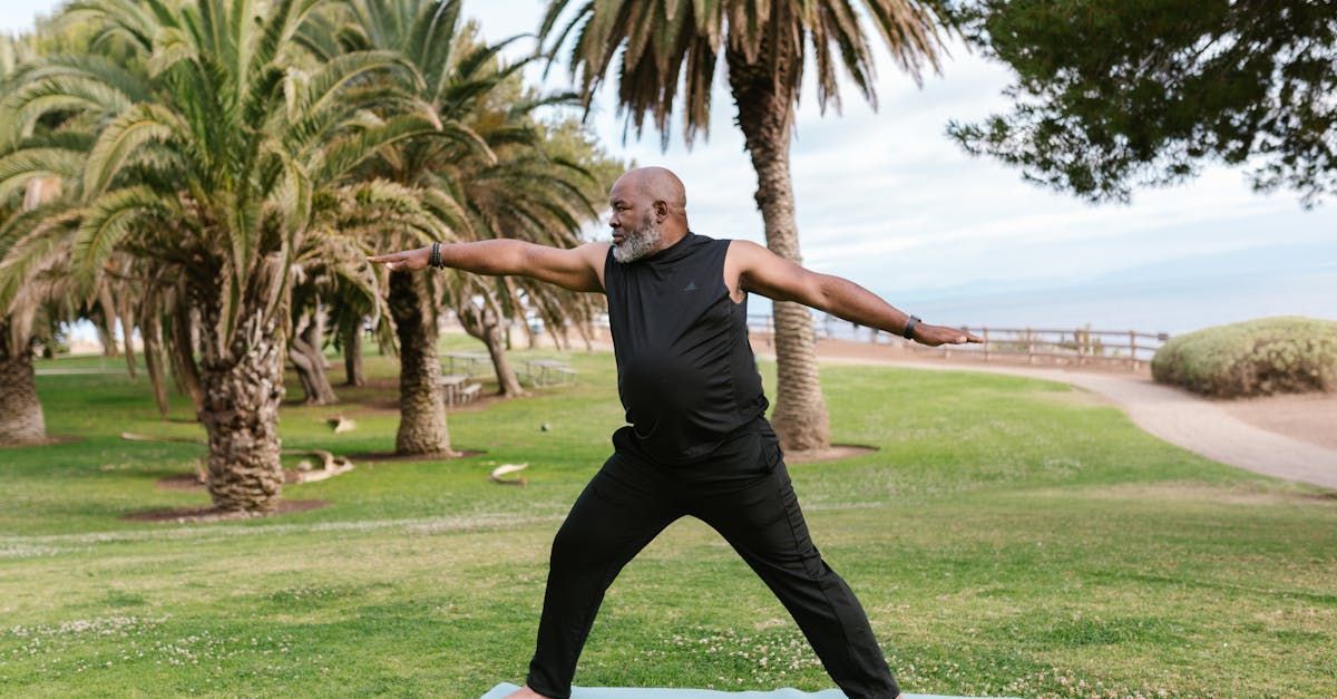 A man is standing on a yoga mat in a park.